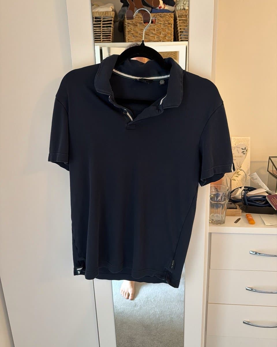 Rami's navy polo on a hanger hooked over his bedroom mirror