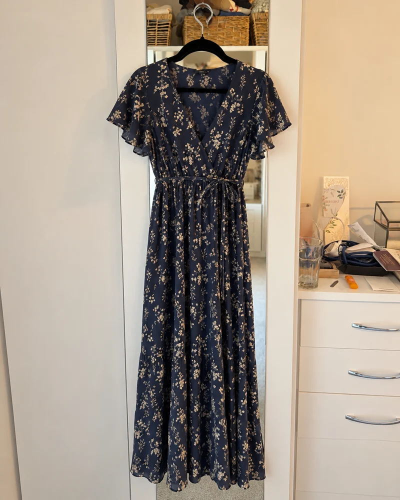 Illustration of a navy floral maxi dress hanging at the bedroom mirror